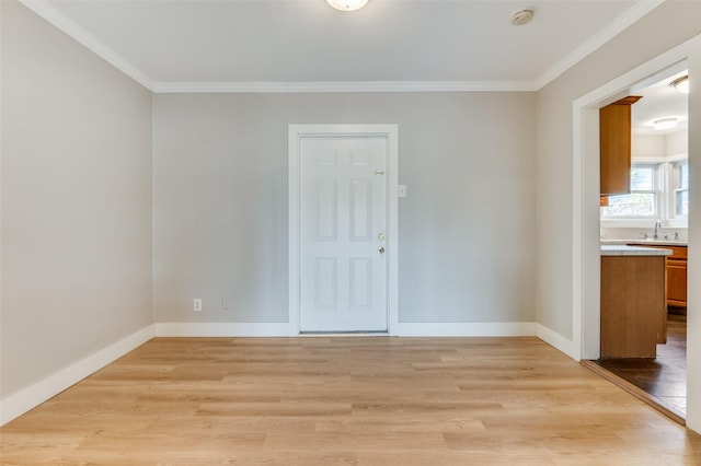 empty room with sink, ornamental molding, and light hardwood / wood-style flooring