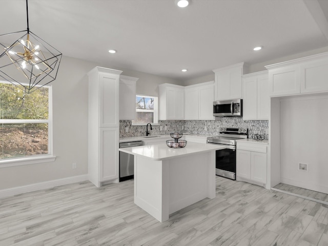 kitchen featuring white cabinetry, decorative light fixtures, a center island, and appliances with stainless steel finishes