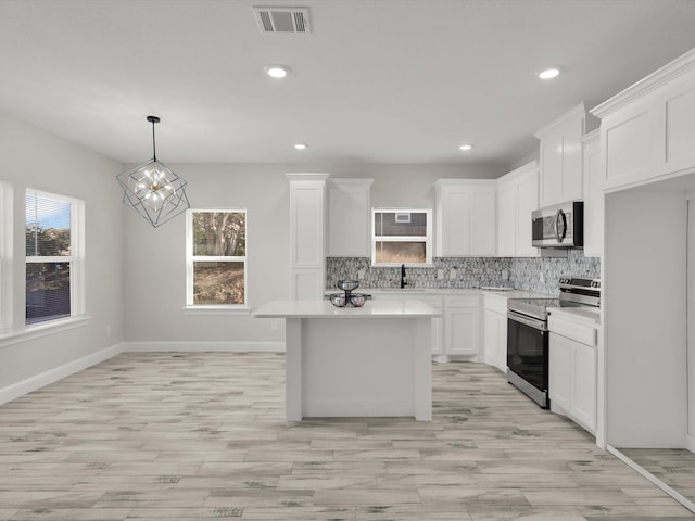 kitchen featuring white cabinetry, appliances with stainless steel finishes, a kitchen island, pendant lighting, and decorative backsplash