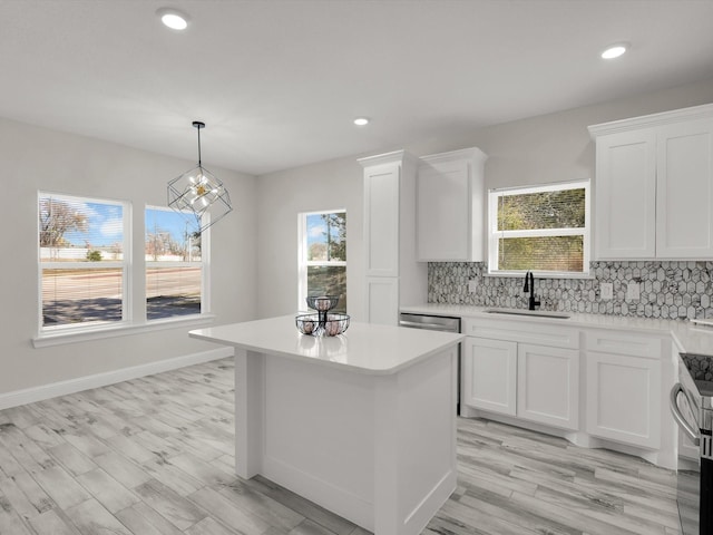 kitchen with white cabinetry, a center island, sink, and backsplash