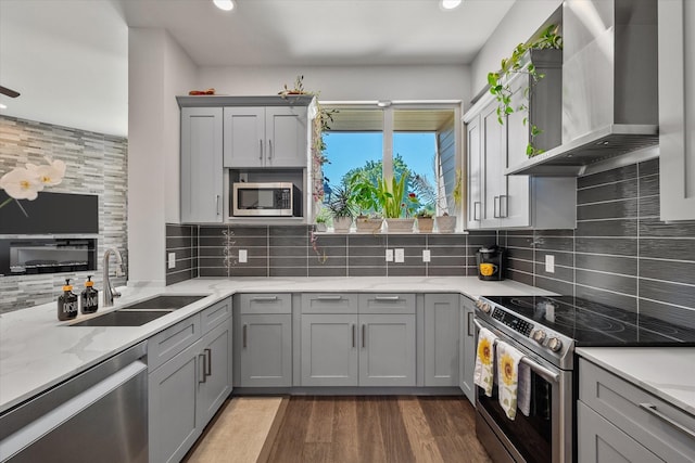 kitchen with gray cabinets, sink, stainless steel appliances, and wall chimney range hood