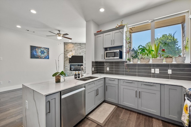 kitchen featuring appliances with stainless steel finishes, tasteful backsplash, gray cabinetry, sink, and dark hardwood / wood-style floors