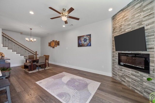 living room featuring a fireplace, ceiling fan with notable chandelier, and dark hardwood / wood-style floors