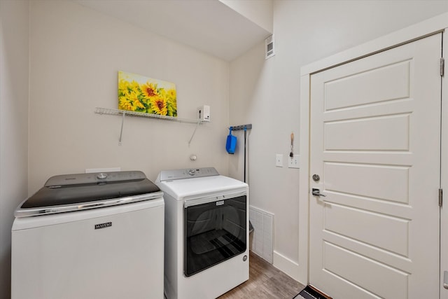 washroom with independent washer and dryer and light hardwood / wood-style flooring