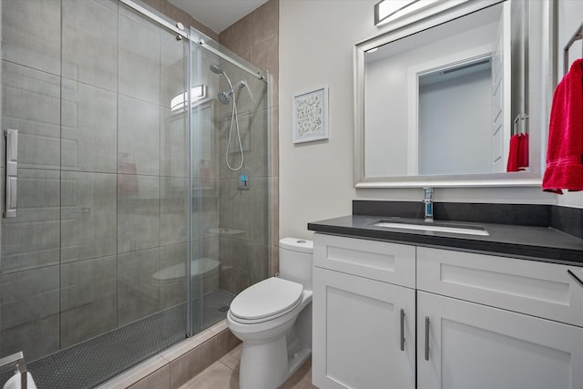 bathroom featuring tile patterned floors, vanity, toilet, and walk in shower