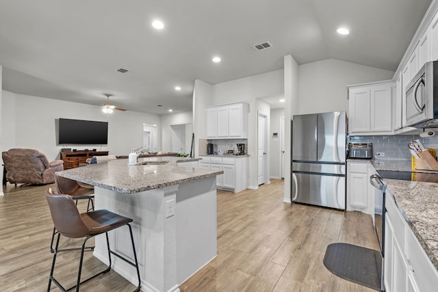 kitchen with tasteful backsplash, a center island with sink, white cabinets, and appliances with stainless steel finishes