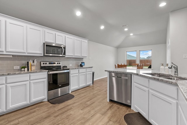 kitchen with lofted ceiling, white cabinetry, sink, and appliances with stainless steel finishes