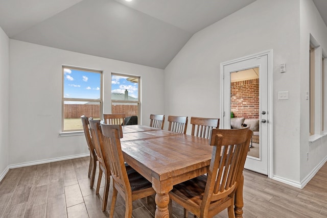 dining area with light wood-type flooring and lofted ceiling