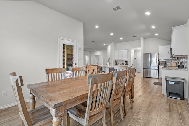 dining area with light hardwood / wood-style flooring and vaulted ceiling