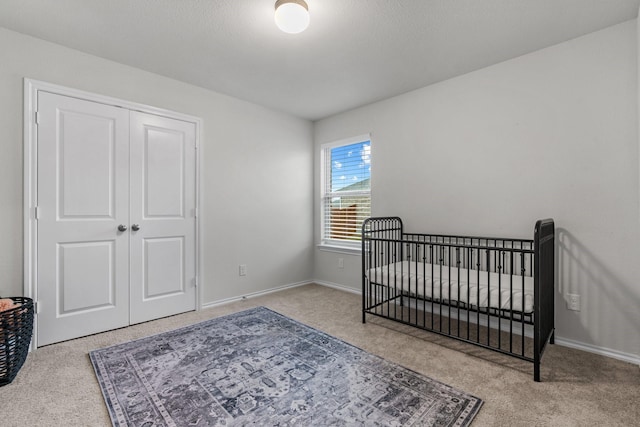 bedroom featuring a crib, light colored carpet, and a closet