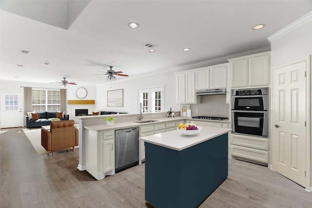 kitchen with sink, appliances with stainless steel finishes, white cabinetry, and a center island