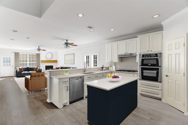 kitchen with appliances with stainless steel finishes, a kitchen island, white cabinetry, sink, and kitchen peninsula