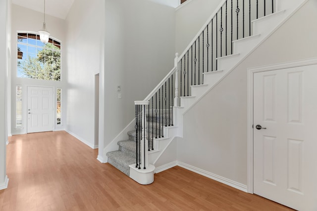 foyer entrance featuring a towering ceiling and hardwood / wood-style flooring