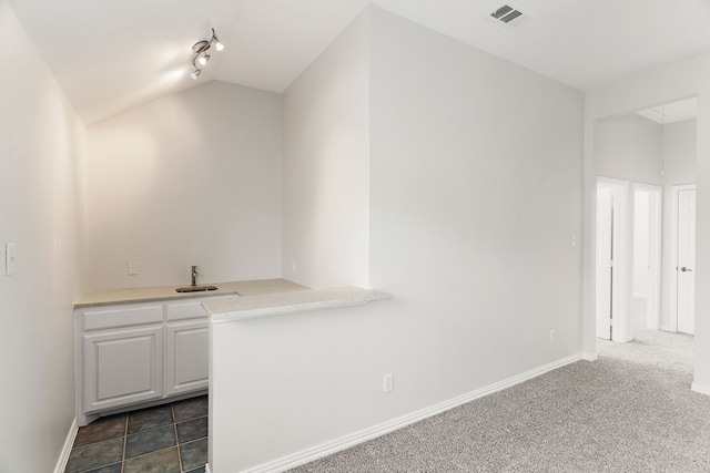 bar with white cabinets, track lighting, vaulted ceiling, and dark carpet