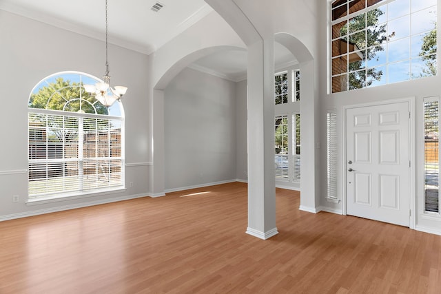 entryway with hardwood / wood-style flooring, crown molding, a chandelier, and plenty of natural light