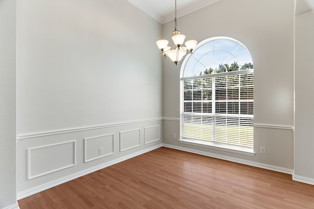 empty room featuring a notable chandelier, ornamental molding, and hardwood / wood-style flooring