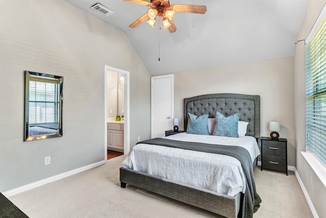 bedroom with ceiling fan, light colored carpet, ensuite bathroom, and vaulted ceiling