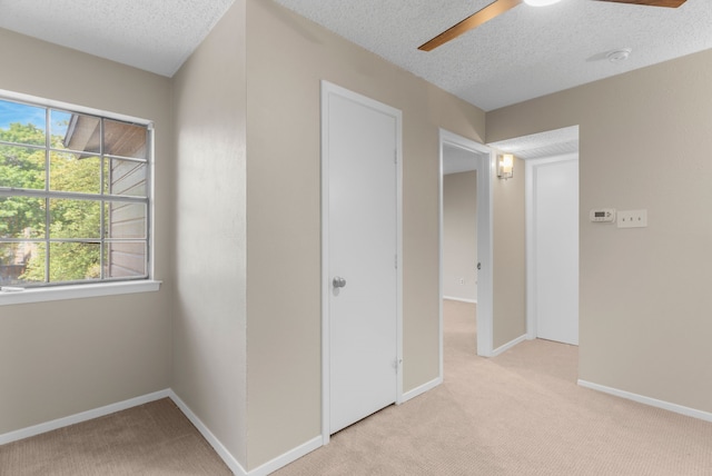 unfurnished bedroom featuring ceiling fan, light carpet, and a textured ceiling