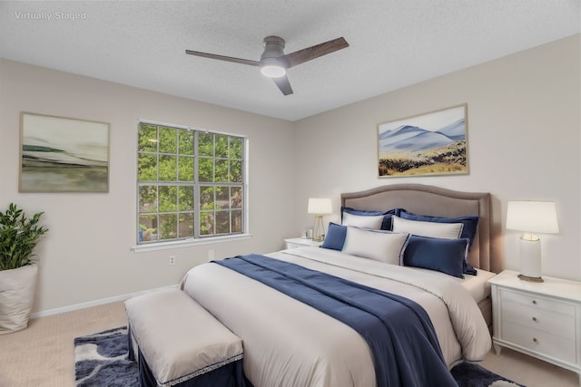 bedroom featuring ceiling fan, light colored carpet, and a textured ceiling