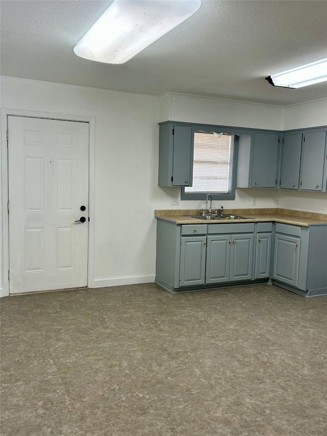 kitchen with gray cabinets, sink, and a textured ceiling