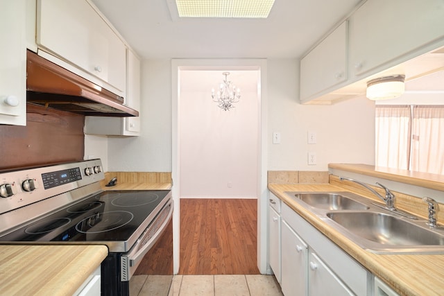 kitchen with stainless steel electric stove, sink, light hardwood / wood-style flooring, an inviting chandelier, and white cabinets