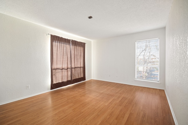 unfurnished room featuring wood-type flooring and a textured ceiling