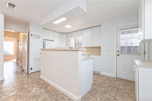 kitchen featuring white refrigerator, white cabinetry, and a wealth of natural light