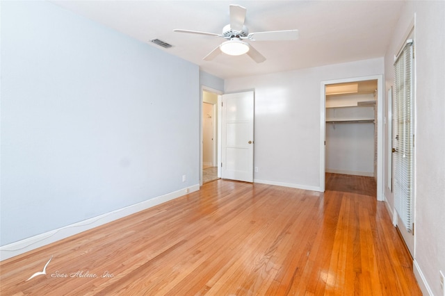 unfurnished bedroom with hardwood / wood-style floors, ceiling fan, a walk in closet, and a closet