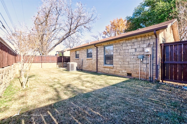 rear view of property featuring central air condition unit and a yard