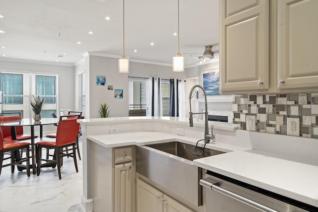 kitchen featuring tasteful backsplash, cream cabinets, sink, and decorative light fixtures