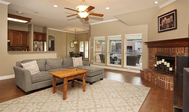 living room featuring ceiling fan, plenty of natural light, dark wood-type flooring, and a brick fireplace