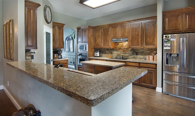 kitchen with a center island, dark hardwood / wood-style floors, decorative backsplash, appliances with stainless steel finishes, and kitchen peninsula