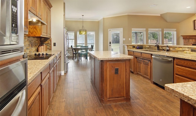 kitchen with appliances with stainless steel finishes, sink, an inviting chandelier, a kitchen island, and hanging light fixtures