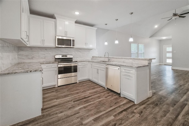 kitchen with kitchen peninsula, appliances with stainless steel finishes, tasteful backsplash, decorative light fixtures, and white cabinetry