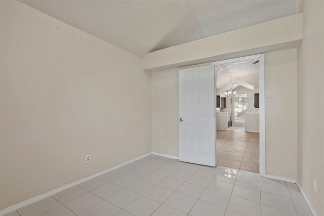 empty room featuring a textured ceiling, light tile patterned floors, lofted ceiling, and an inviting chandelier