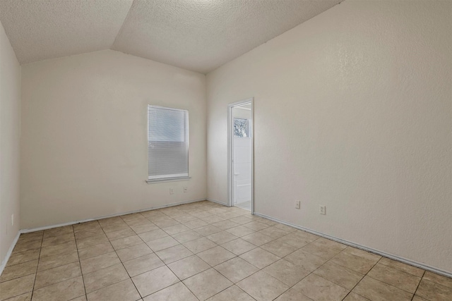 tiled spare room with a textured ceiling and vaulted ceiling