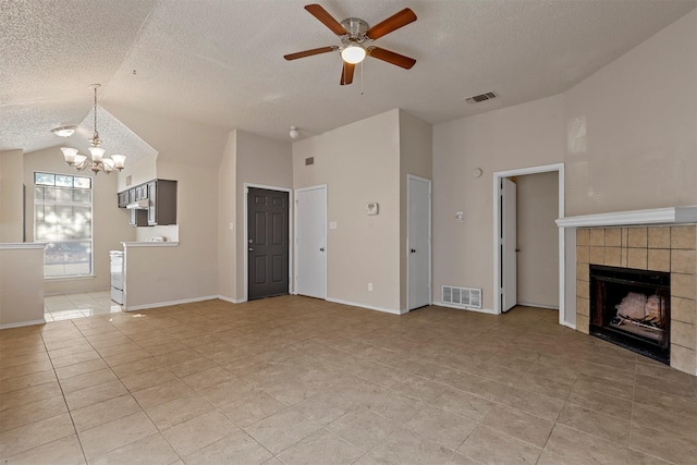 unfurnished living room featuring a tile fireplace, a textured ceiling, lofted ceiling, light tile patterned flooring, and ceiling fan with notable chandelier