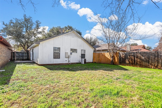 rear view of house with cooling unit and a yard