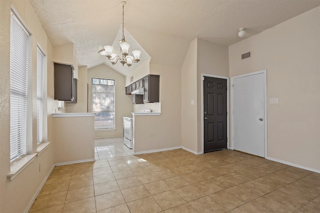 kitchen with a notable chandelier, white range oven, a textured ceiling, lofted ceiling, and light tile patterned flooring