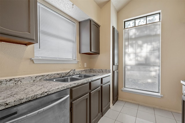 kitchen featuring sink, light tile patterned floors, stainless steel dishwasher, and lofted ceiling