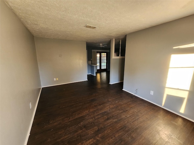 empty room featuring french doors, dark hardwood / wood-style flooring, a textured ceiling, and ceiling fan