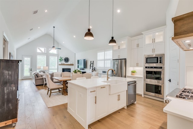 kitchen featuring appliances with stainless steel finishes, tasteful backsplash, pendant lighting, white cabinetry, and an island with sink