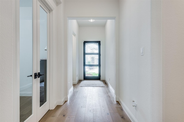 hallway with french doors and light hardwood / wood-style floors