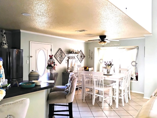 tiled dining room with a textured ceiling, ceiling fan, and ornamental molding