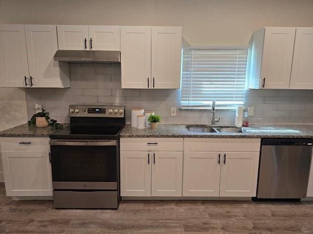 kitchen with white cabinets, sink, dark stone countertops, light wood-type flooring, and appliances with stainless steel finishes