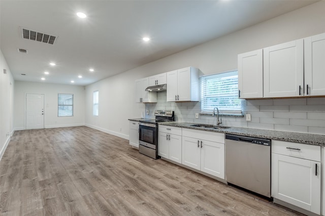 kitchen with light stone countertops, white cabinetry, sink, stainless steel appliances, and light hardwood / wood-style floors