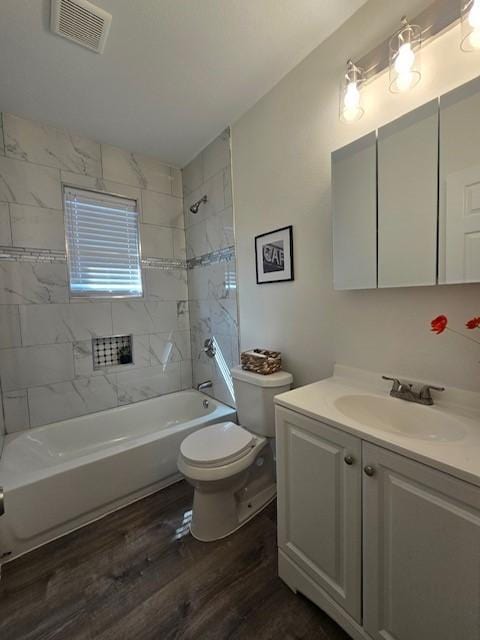 full bathroom featuring hardwood / wood-style flooring, vanity, toilet, and tiled shower / bath