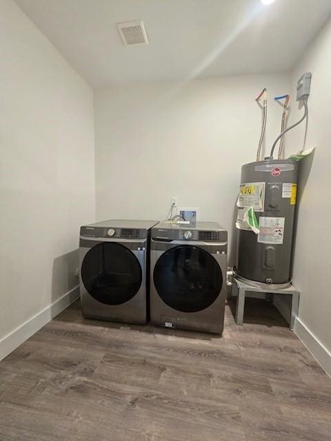 laundry area featuring hardwood / wood-style flooring, washing machine and dryer, and electric water heater