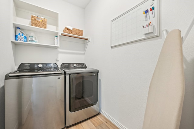 clothes washing area with light hardwood / wood-style floors and washer and dryer