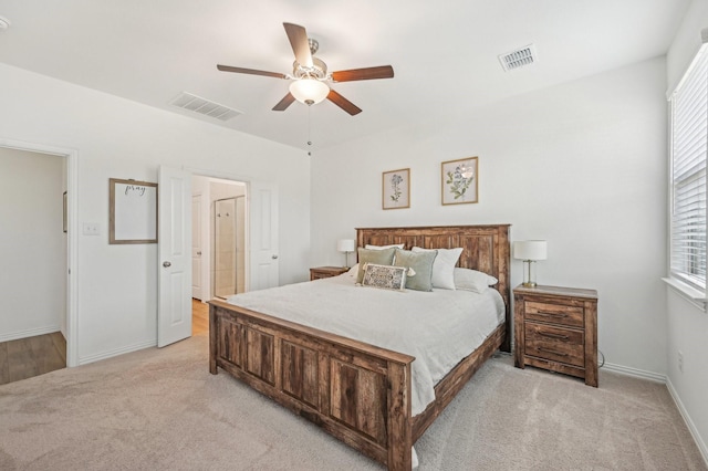 bedroom with visible vents, light carpet, baseboards, and a ceiling fan